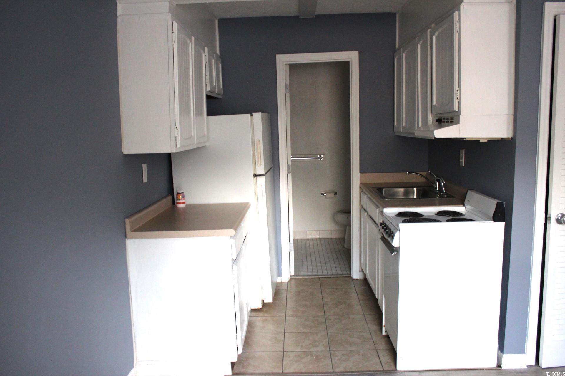 1500 Chester Street, Unit 2 Myrtle Beach, SC 29577 - Photo 4 of 9 Kitchen with white appliances, white cabinetry, light tile patterned floors, and light countertops
