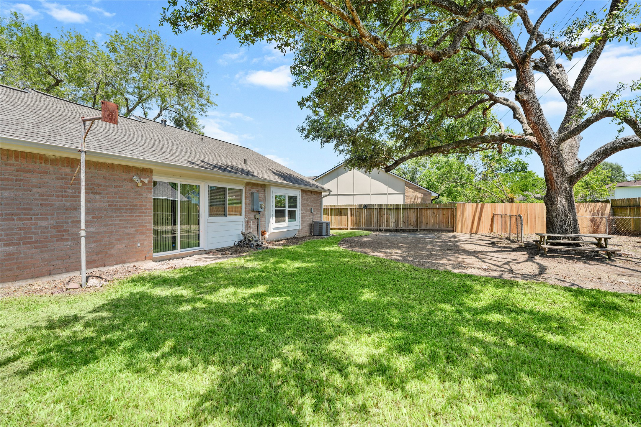 6610 Blue Ridge Drive Richmond, TX 77469 - Photo 22 of 24 Spacious backyard with lush green grass and a large, mature tree providing shade. Surrounded by a wooden fence, offering privacy and a serene atmosphere. Ideal for outdoor activities and relaxation.