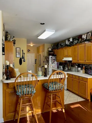 a kitchen with stainless steel appliances granite countertop a refrigerator a stove top oven a sink a dining table and chairs with wooden floor