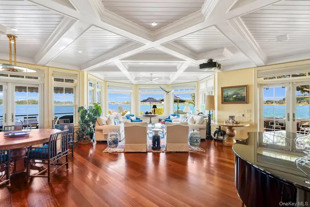 a living room with lots of furniture wooden floor and large windows