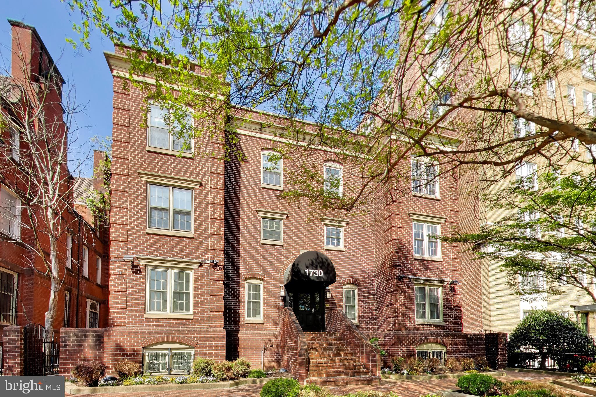 a front view of a building with lot of trees