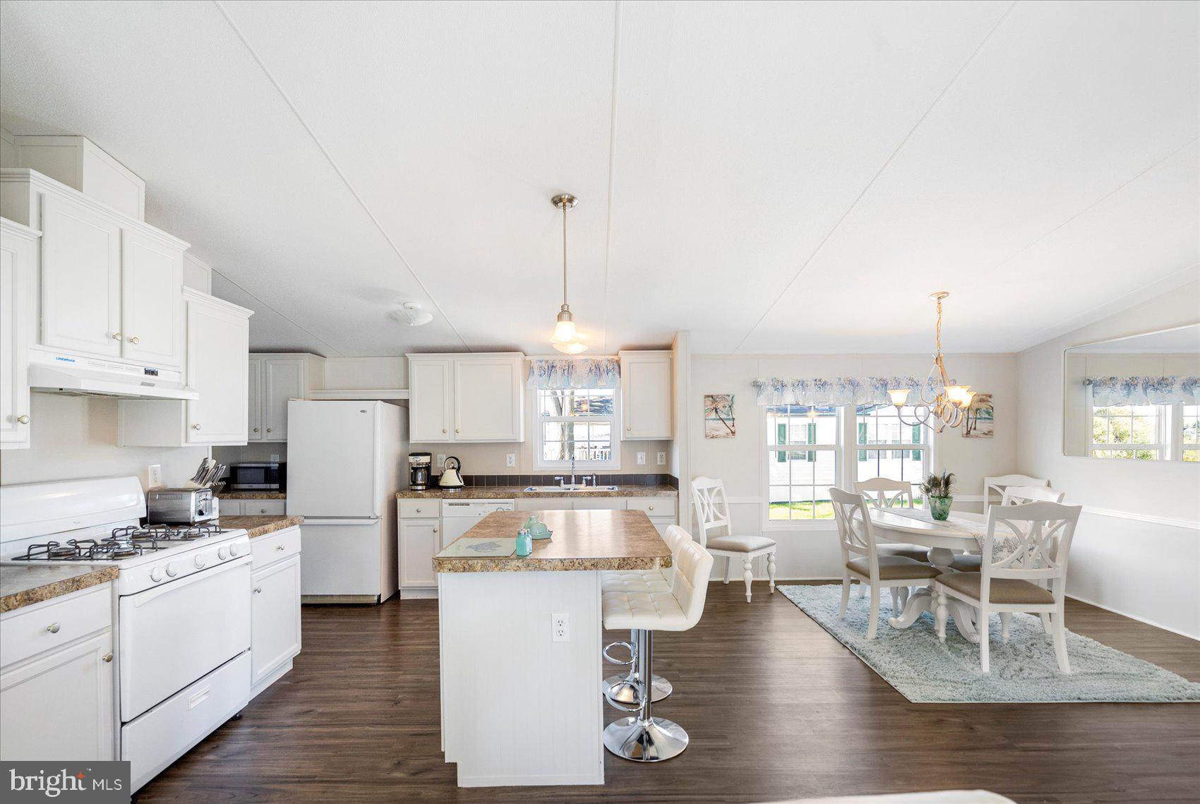 28 Shore Road Sparrows Point, MD 21219 - Photo 10 of 20 a kitchen with stainless steel appliances kitchen island granite countertop a stove top oven a sink a dining table and chairs with wooden floor
