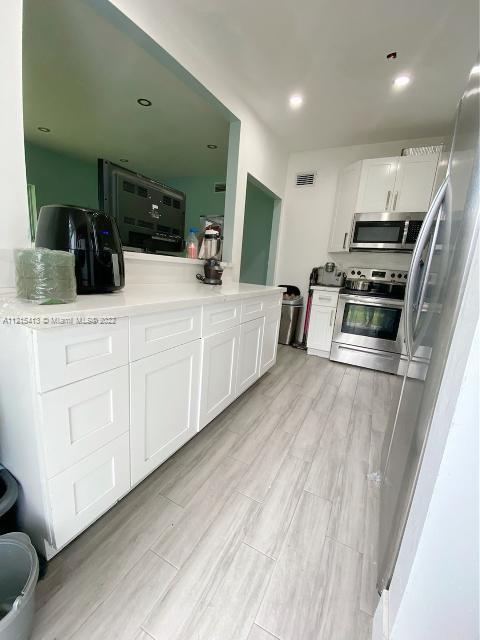 a large white kitchen with a sink and dishwasher a stove with wooden floor