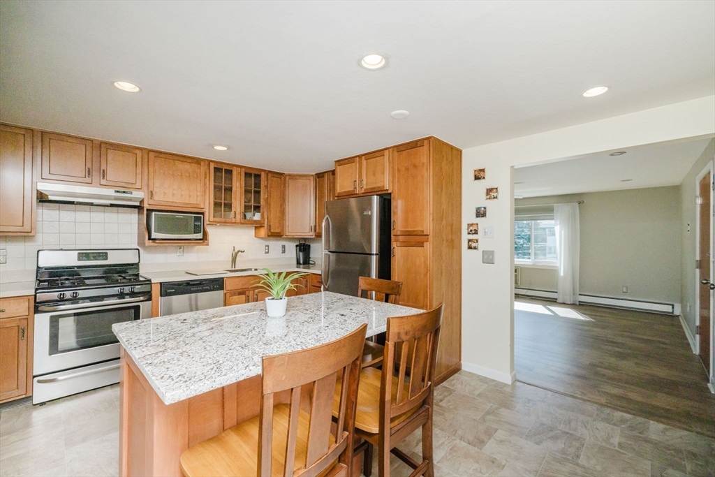 43 Will Drive, Unit 30 Canton, MA 02021 - Photo 7 of 25 a kitchen with stainless steel appliances granite countertop a refrigerator a stove top oven a sink dishwasher and white cabinets with wooden floor
