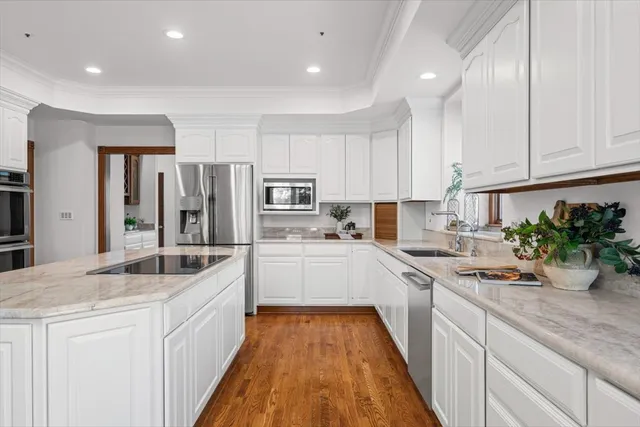 a large kitchen with stainless steel appliances a large counter top a stove a sink dishwasher and a refrigerator