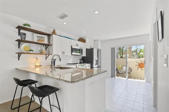 a kitchen with stainless steel appliances granite countertop a sink and a refrigerator