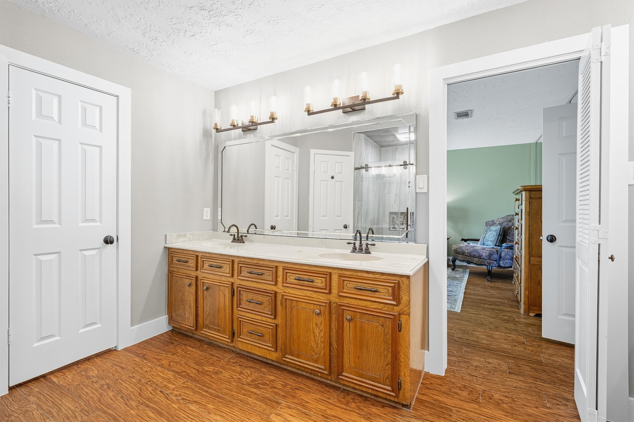 826 North Rivershire Drive Conroe, TX 77304 - Photo 21 of 46 The primary bath opens with a wide double vanity, cultured marble countertops, wood cabinetry, and a Hollywood style light bar that makes the whole space feel bright and intentional. Two doors mean two closets, and yes that matters.
