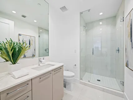 a bathroom with a shower sink vanity mirror and toilet