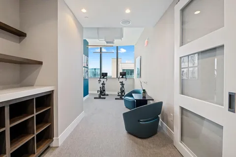 a work room with furniture a flat screen tv and a large window