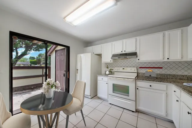 a kitchen with granite countertop white cabinets and stainless steel appliances
