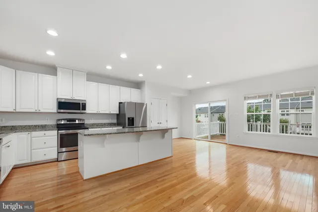 a kitchen with stainless steel appliances granite countertop a refrigerator a sink a stove a microwave and island