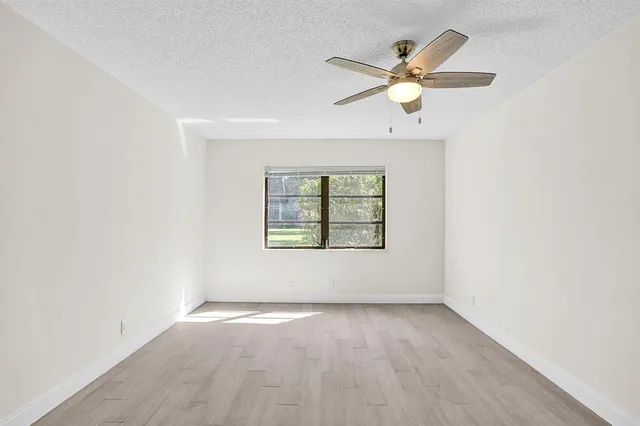an empty room with a window and a fan