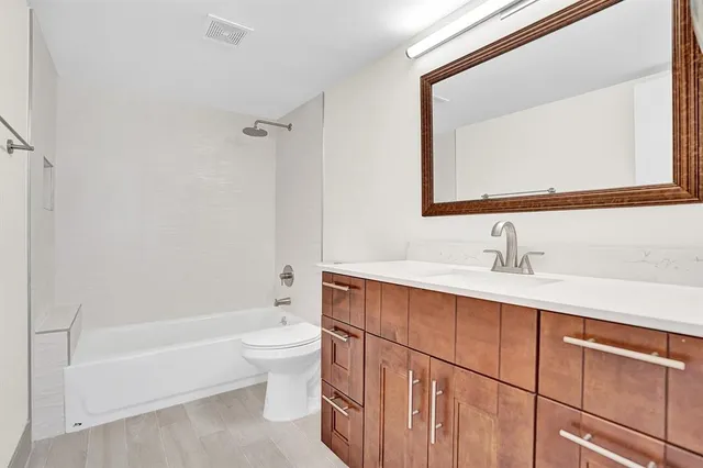 a bathroom with a bathtub shower sink vanity and toilet