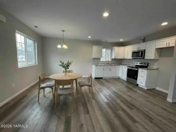 a kitchen with microwave a stove a sink dishwasher a dining table and chairs with wooden floor