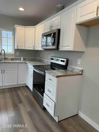 a kitchen with granite countertop white cabinets and white appliances