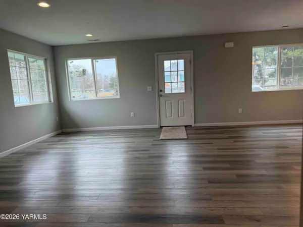 an empty room with wooden floor and windows