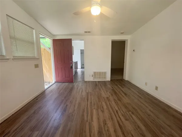 an empty room with wooden floor and windows