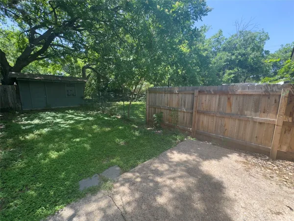 a backyard of a house with plants and large trees