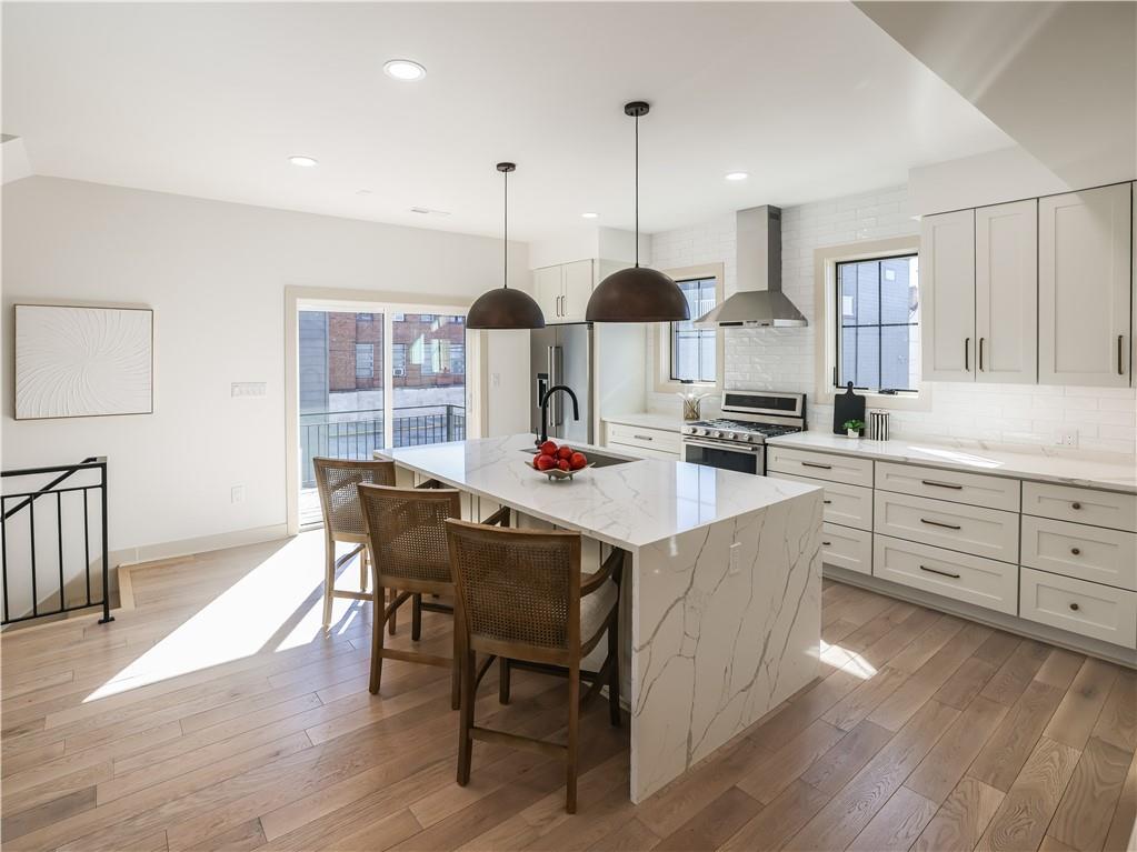 909 Rickenbach Street Pittsburgh, PA 15212 - Photo 6 of 23 a kitchen with stainless steel appliances kitchen island granite countertop a sink a stove and chairs