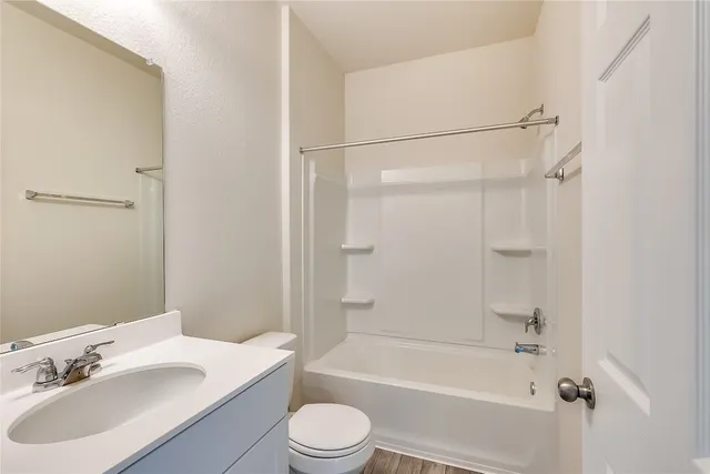 a bathroom with a bathtub shower sink vanity mirror and toilet