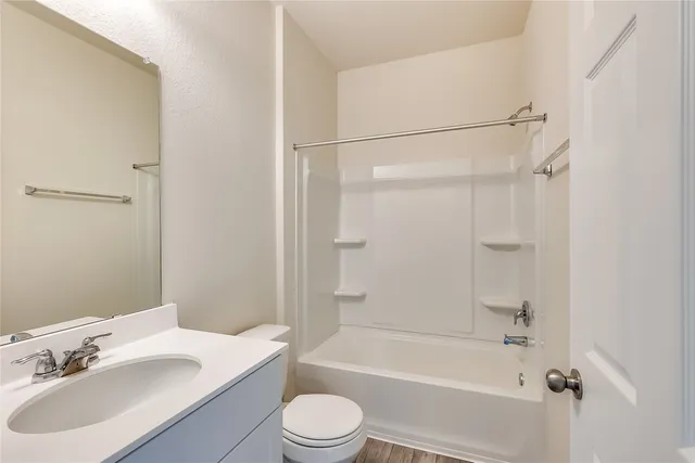 a bathroom with a bathtub shower sink vanity mirror and toilet