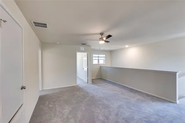 a view of an empty room with window and chandelier fan