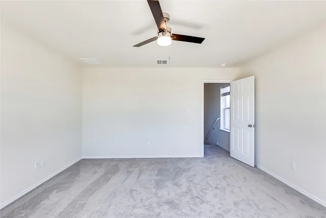 an empty room with a ceiling fan and carpet