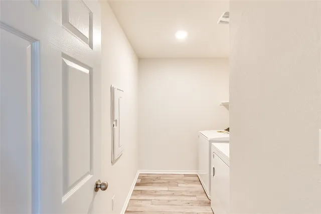 a view of a hallway with wooden floor and a bathroom