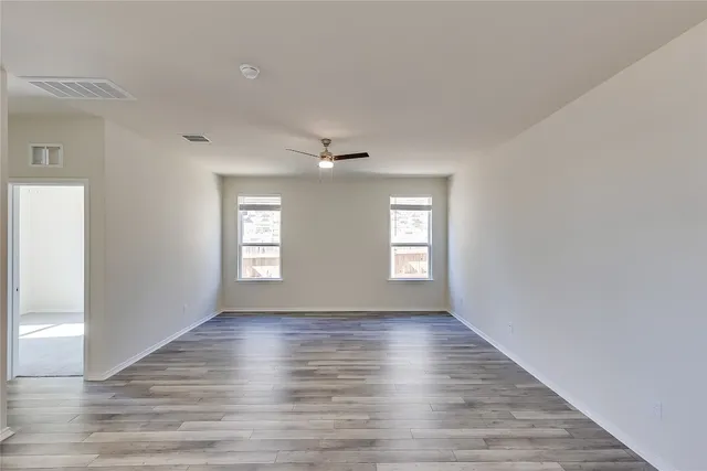a view of an empty room with wooden floor and window