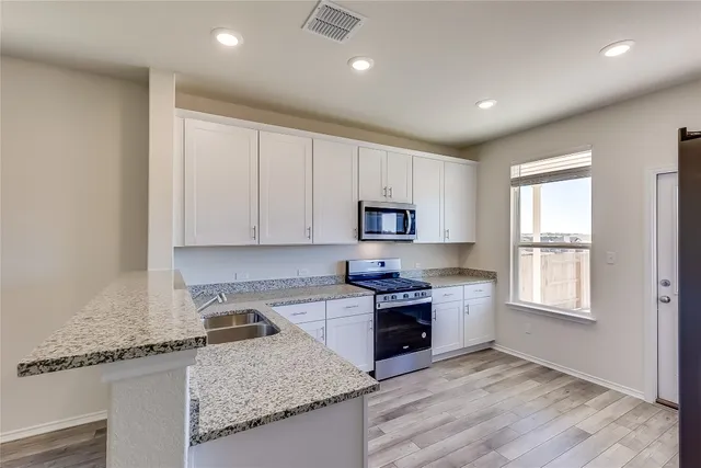 a kitchen with granite countertop a stove sink and cabinets