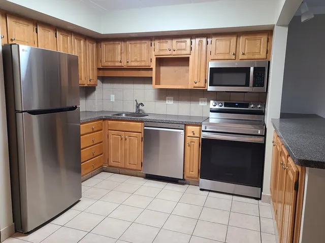 a kitchen with granite countertop a refrigerator stove and microwave