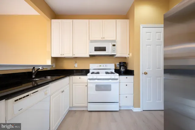 a kitchen with granite countertop white cabinets and white appliances