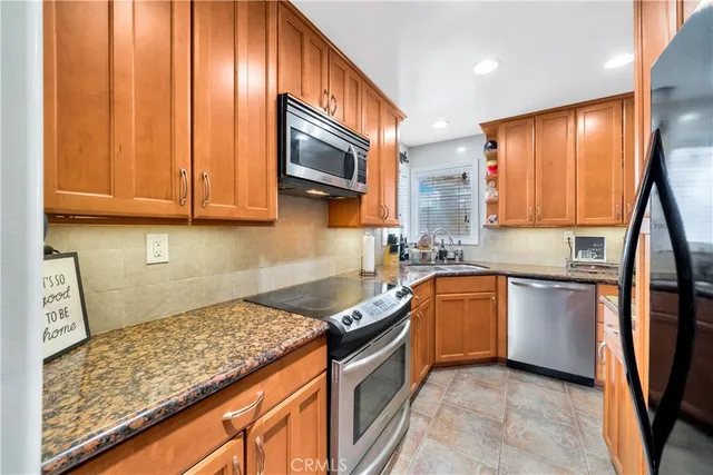 a kitchen with stainless steel appliances granite countertop a refrigerator a stove top oven and sink