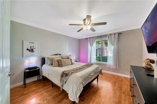 a bedroom with a bed and a dresser with wooden floor