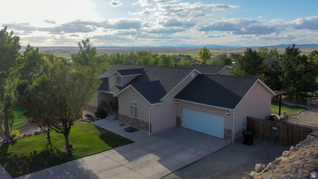 Stucco exterior with stone accenting, a dark shingle roof, and an attached two-car garage