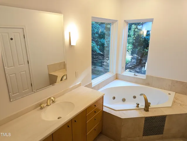 a bathroom with a tub sink and mirror