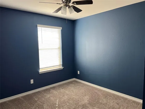an empty room with a ceiling fan and carpet