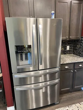 a metallic refrigerator freezer sitting inside of a kitchen