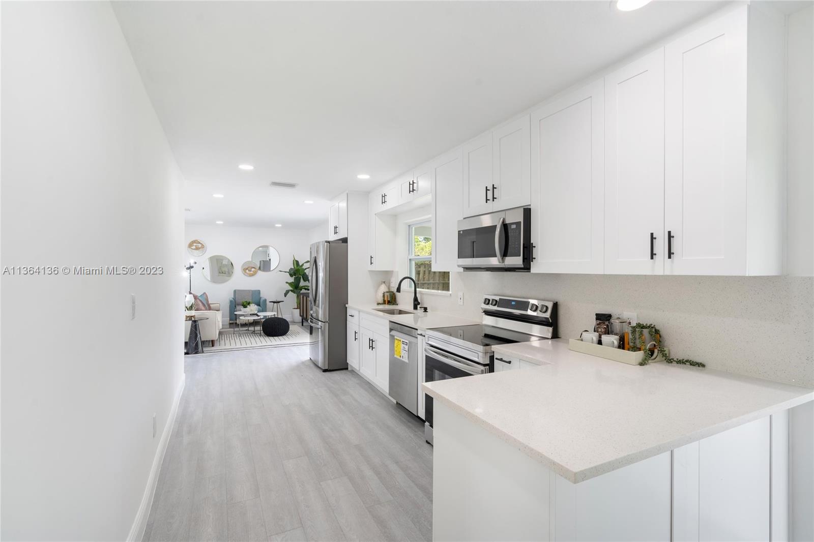 7321 Northwest 11th Place Plantation, FL 33313 - Photo 8 of 23 a kitchen with stainless steel appliances a stove top oven a sink a refrigerator white cabinets and wooden floor