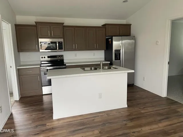 a utility room with stainless steel appliances wooden floor and view living room