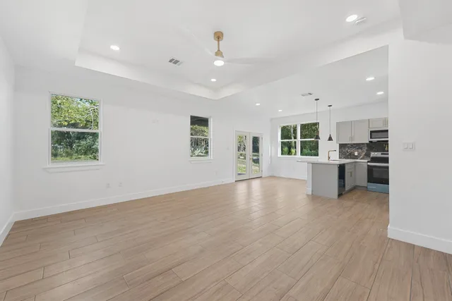 an empty room with wooden floor and a kitchen