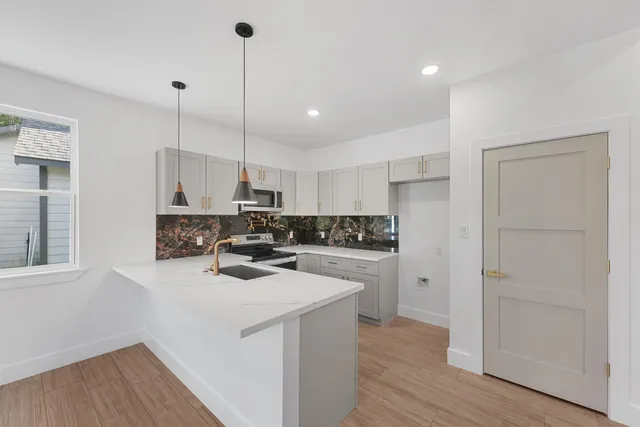 a kitchen with refrigerator a stove a sink and white cabinets with wooden floor