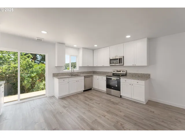 a kitchen with wooden floors stainless steel appliances and white cabinets