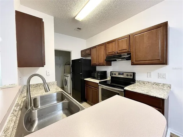 a kitchen with stainless steel appliances wooden cabinets a sink and a stove
