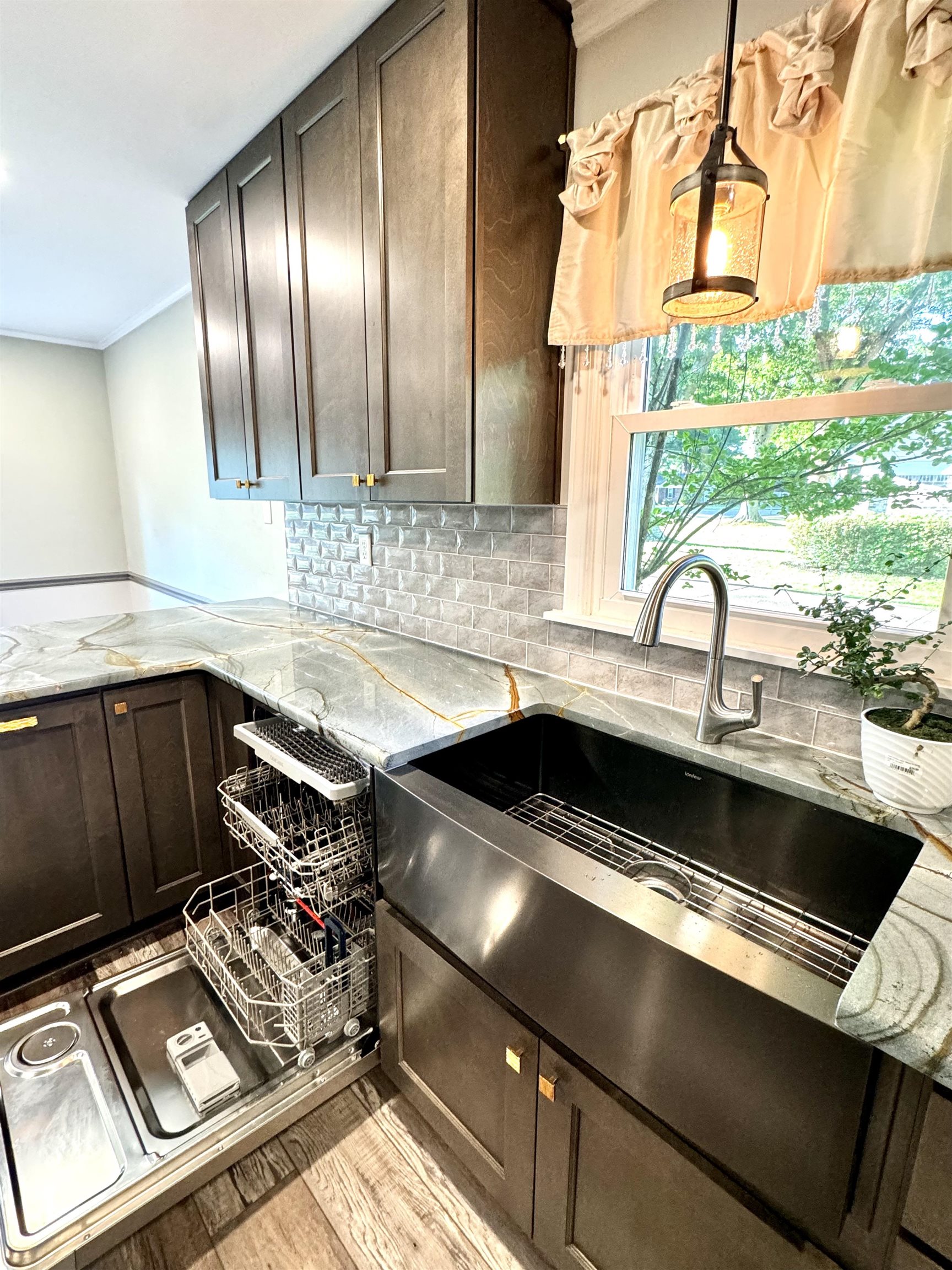 641 Hermitage Trail Collierville, TN 38017 - Photo 11 of 24 Modern kitchen featuring dark wood-finish cabinetry with gold-tone hardware, a stainless steel farmhouse sink, and patterned stone countertops