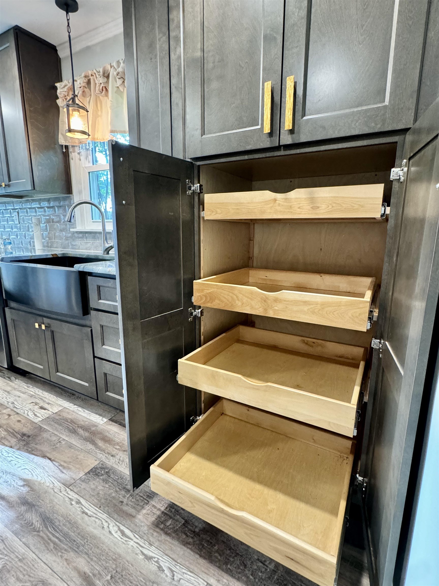 641 Hermitage Trail Collierville, TN 38017 - Photo 12 of 24 Kitchen pantry with pull-out drawers, dark wood-finish cabinetry, gold-tone hardware, wood-finish flooring, and a farm sink with a gray tile backsplash