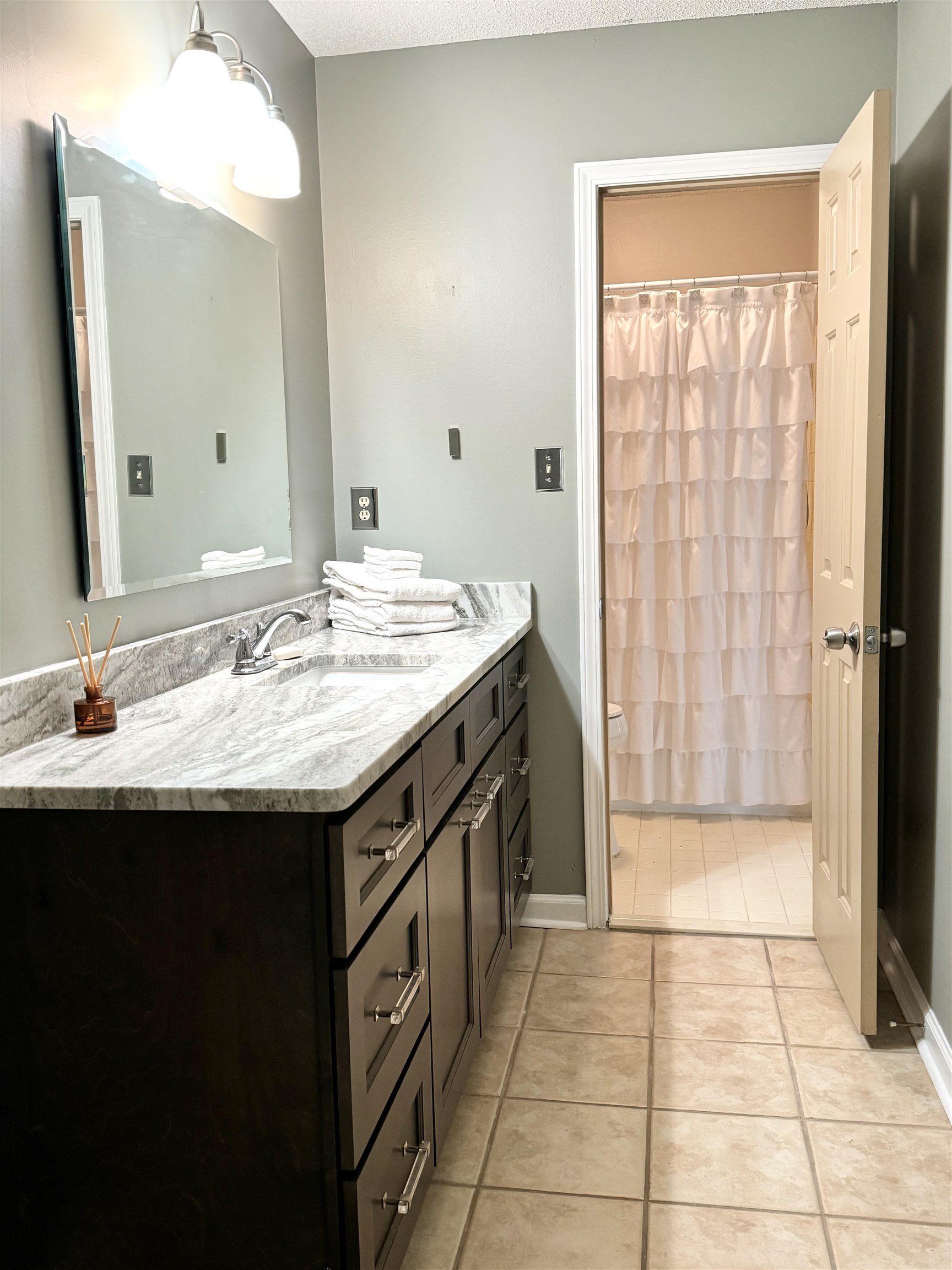 641 Hermitage Trail Collierville, TN 38017 - Photo 22 of 24 Bathroom vanity featuring a light-toned stone countertop, integrated sink, and dark wood-finish cabinetry with brushed nickel hardware
