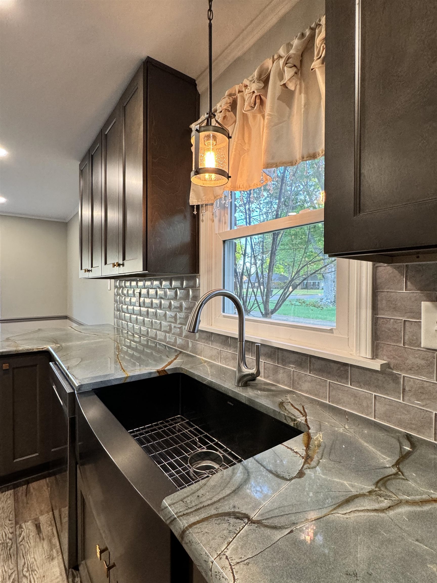 641 Hermitage Trail Collierville, TN 38017 - Photo 9 of 24 Kitchen featuring rich cabinetry, a deep basin sink, stone countertops with distinctive veining, a subway tile backsplash, and an overhead pendant light