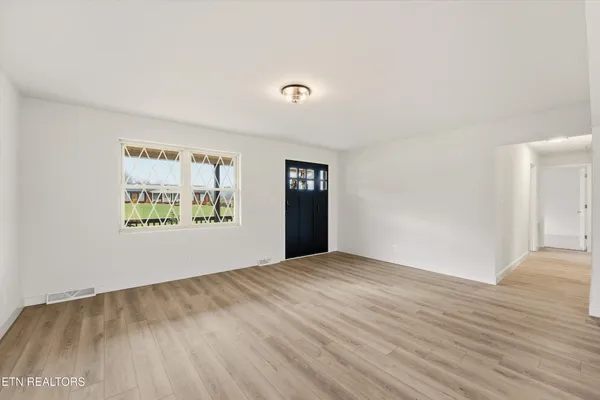 a large kitchen with stainless steel appliances granite countertop a refrigerator oven a sink dishwasher and white cabinets with wooden floor