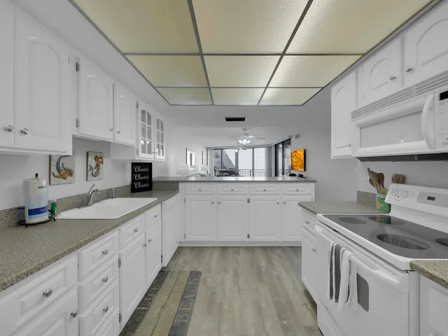 a kitchen with granite countertop white cabinets and white appliances